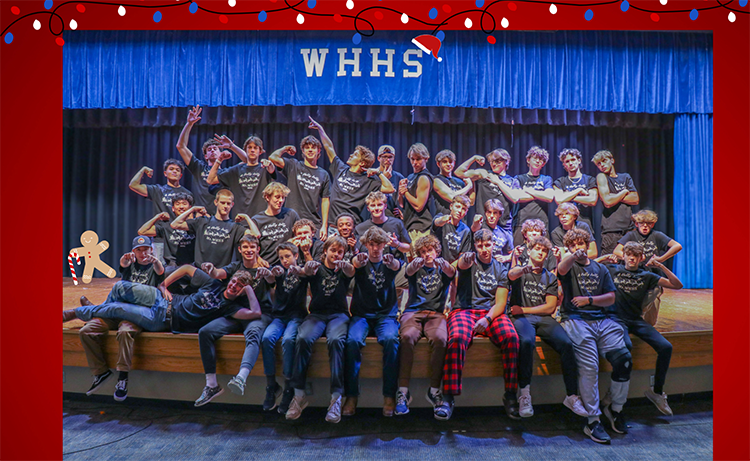 34 Mr. WHHS contestants pose for a photo in a fun way on stage. Behind the contestants is a blue "WHHS" stage curtain.