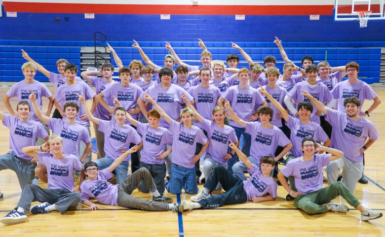 A group photo of 36 contestants in the Mr. WHHS pageant. Each student is striking a pose for a fun picture. They are all wearing matching purple shirts to fit the theme.