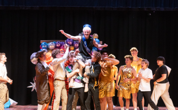 About 20 contestants lifting up the winner on stage. The winner is wearing a Mr. WHHS sash and crown.